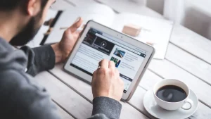 Person Using Tablet With Coffee Cup On Table